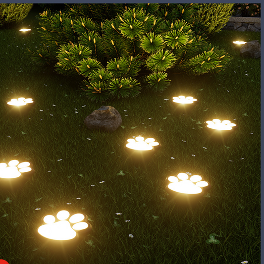 Solar paw print memorial lights glowing on a lawn at night